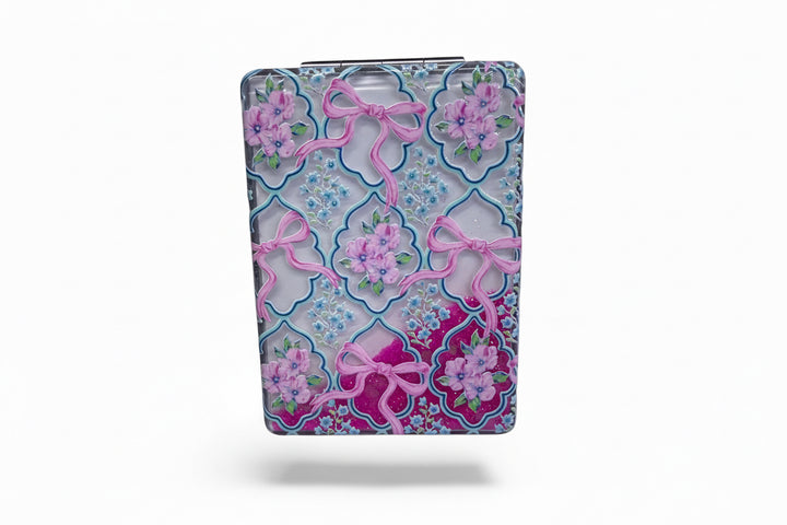 Compact mirror with pink bows and flowers on blue-purple geometric design. Available in small and large sizes.