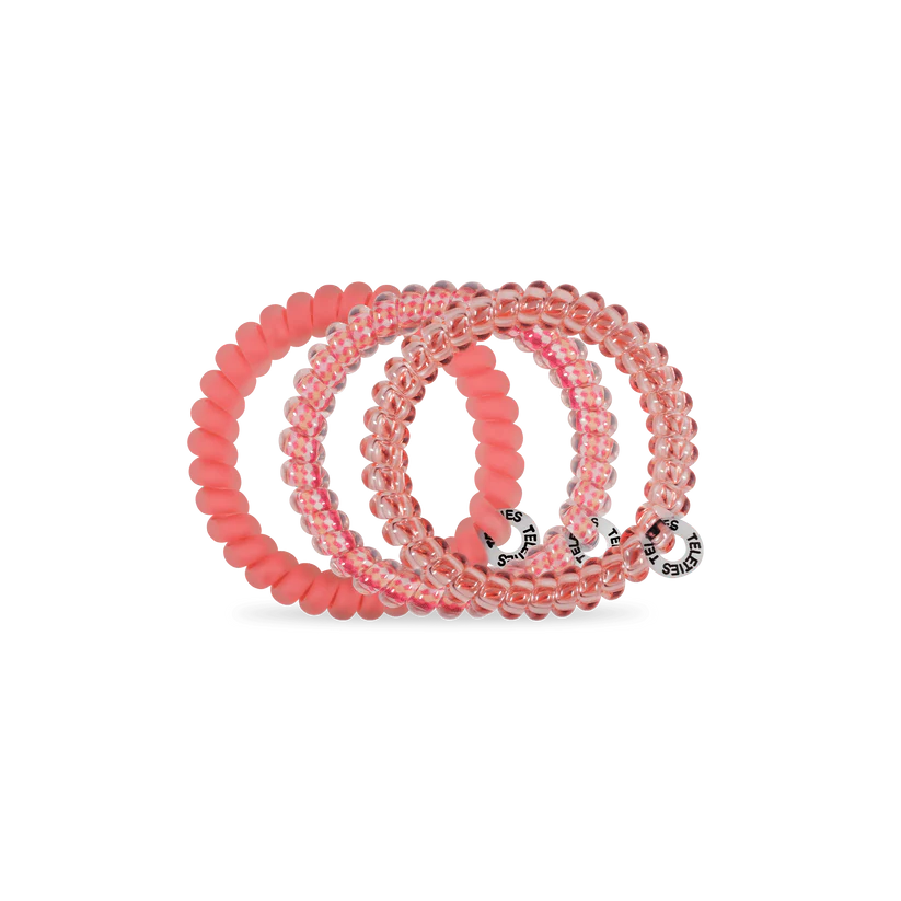 Three TELETIES Hair Ties in clear pink and solid pink, spiral-shaped with logo tags. Available in small and large sizes.