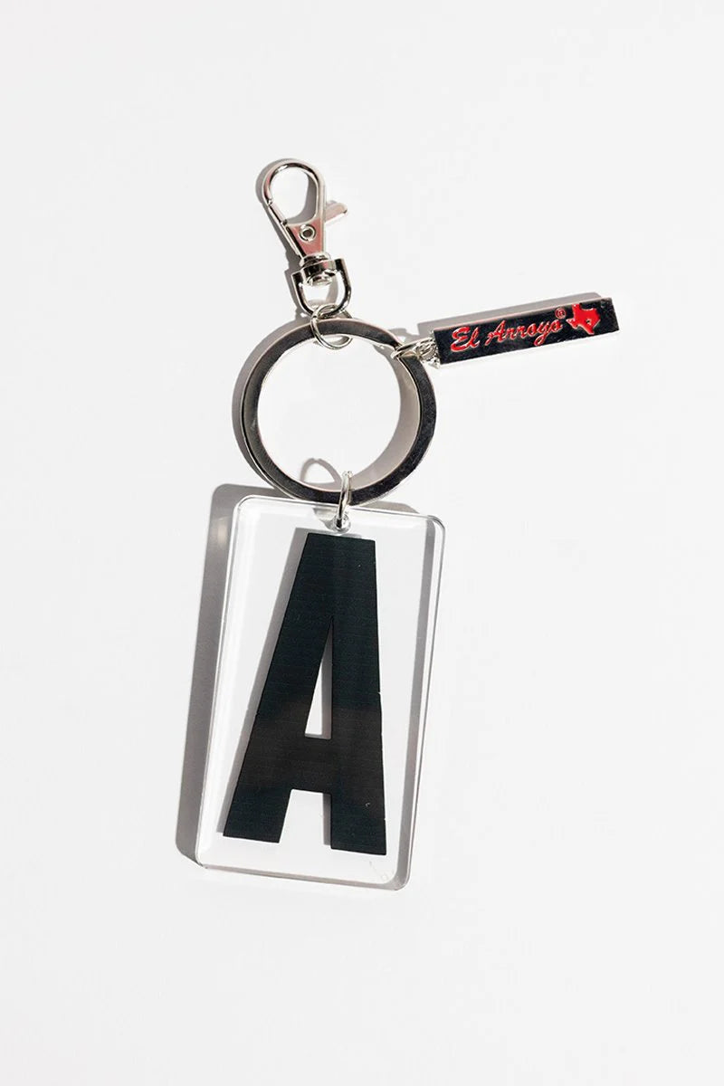 Clear acrylic keychain with bold black "A," silver ring, clasp, and small black tag. Available in standard size only.