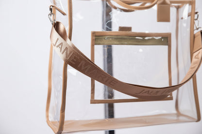 Goldie Multi Purpose Tote: clear PVC with beige trim, beige “JANE MARIE” strap, exterior zippered pocket, silver hardware. Sizes available: Small, Medium, Large.