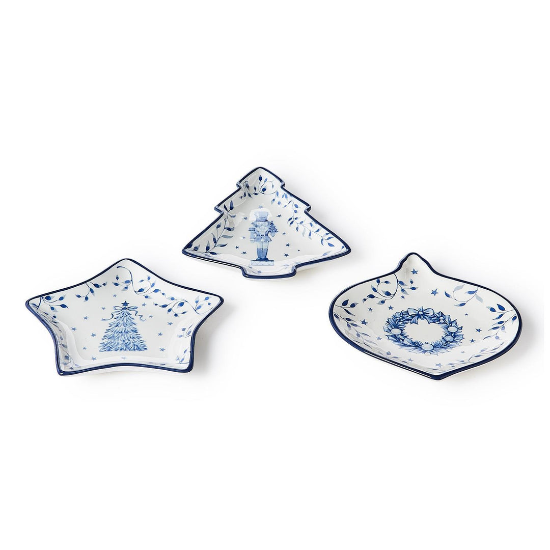 Three Season’s Gala Tidbit dishes in white ceramic with blue rims, featuring illustrations of a Christmas tree, a nutcracker, and a holiday wreath.