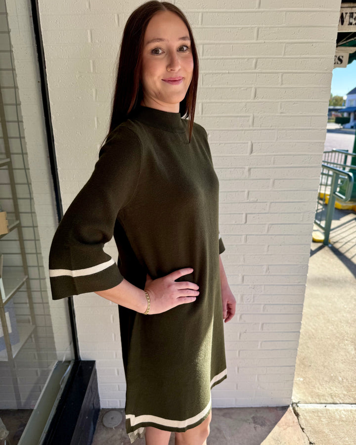 Olive green mock neck sweater dress with three-quarter length sleeves and white contrast trim at cuffs and hem. Available in multiple sizes.