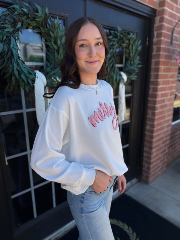 White Sarah Merry Boucle Sweatshirt with pink embroidered “merry” script. Available sizes not specified.