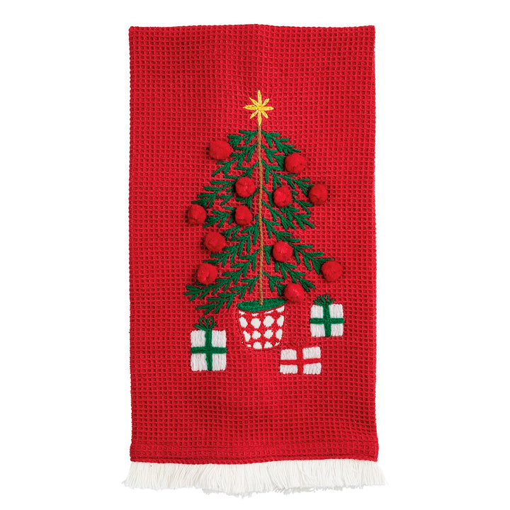 Red waffle knit hand towels featuring an embroidered Christmas tree with pom-poms, star topper, and gift boxes, finished with white fringe.