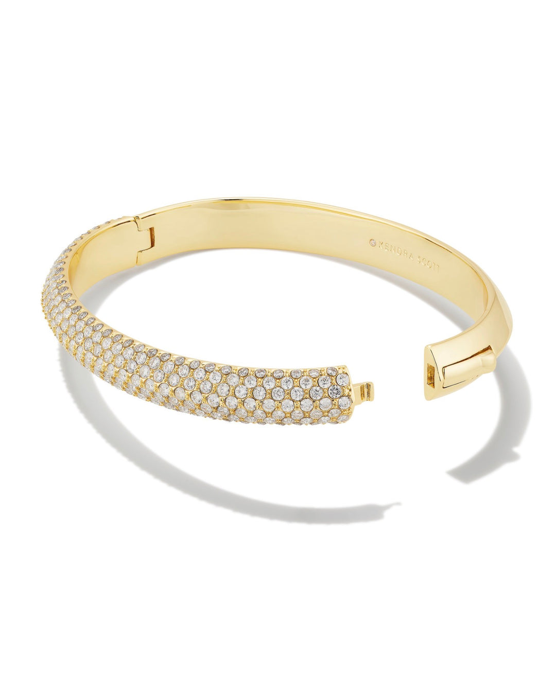 The Mini Elton Luxe Cuff White CZ by Kendra Scott is a slim gold bangle with a hinged clasp and half-encrusted white cubic zirconia. Available in small, medium, and large sizes.