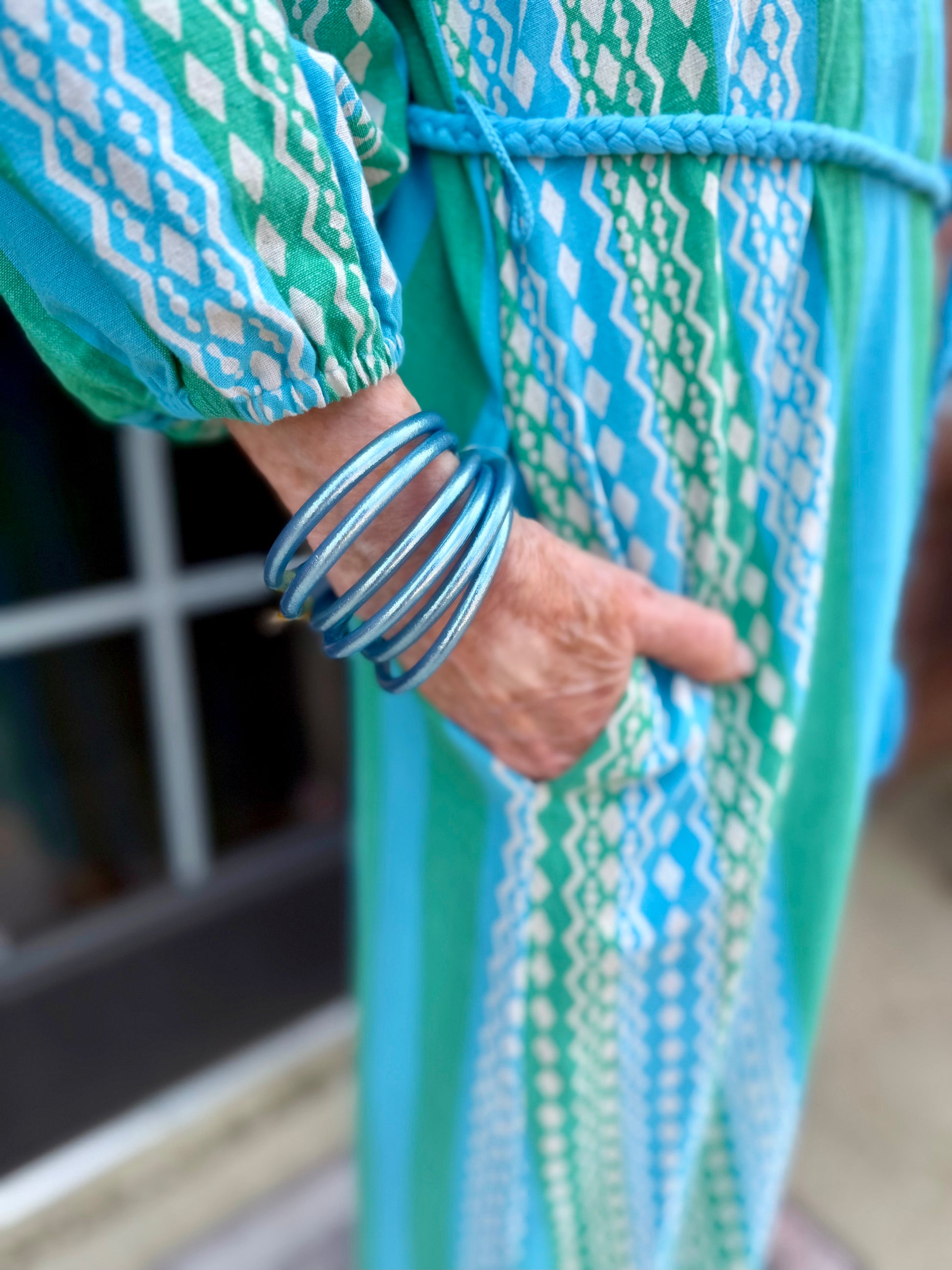 Patio Dress with blue and green stripes, braided belt, and pockets. Available in sizes XS–XL.