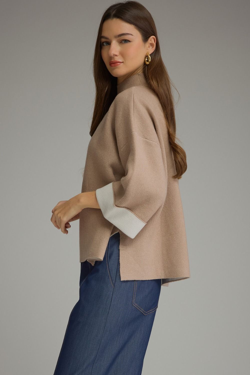 Tan contrast mock neck sweater with mock neck, wide three-quarter sleeves, white cuffs, and side slits.