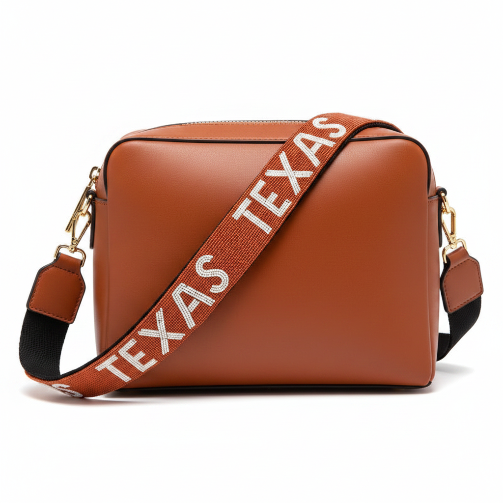Brown rectangular crossbody bag with a beaded orange strap reading “TEXAS” in white and black-edged letters, finished with gold hardware. Available in multiple sizes.