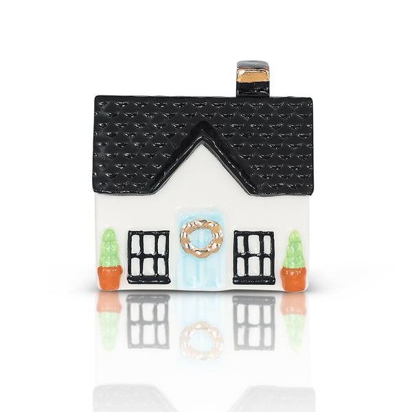 Small ceramic house figurine with black roof, white walls, blue wreath door, and two potted plants; available in one size.
