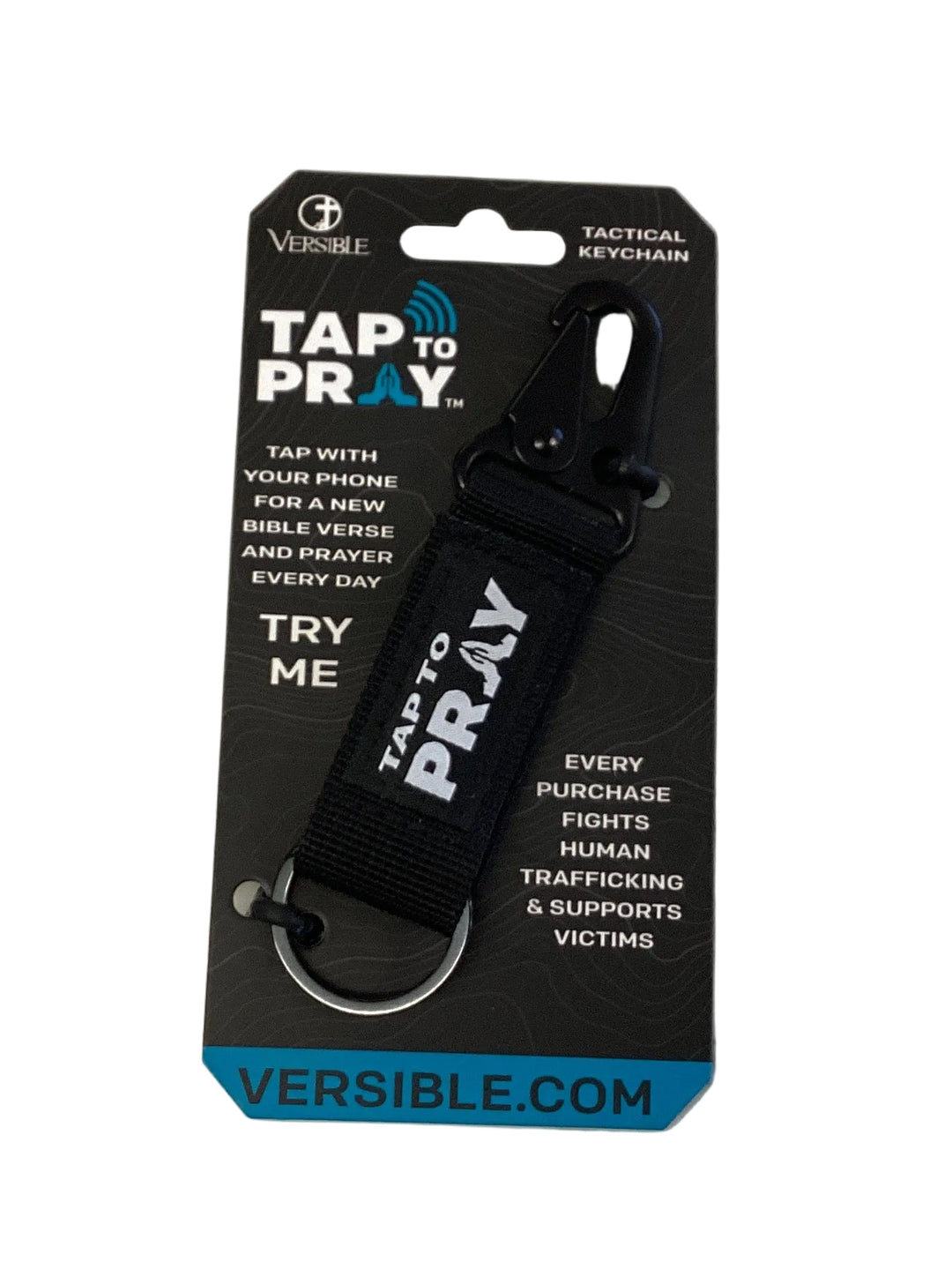 Black fabric Tap To Pray keychain with clip and ring on a display card, supporting the fight against human trafficking.