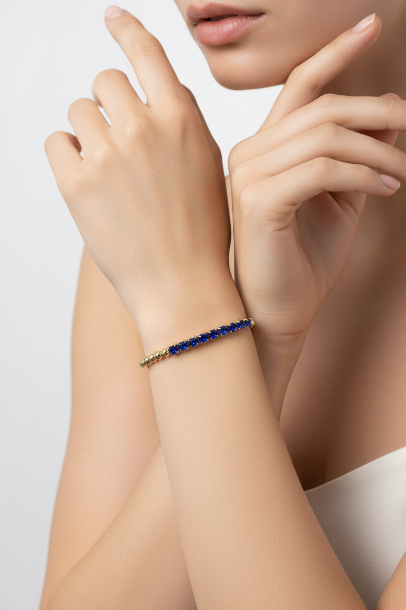 Gold beaded stretch bracelet with dark blue rectangular gemstones. Water resistant. Available in S, M, and L sizes.
