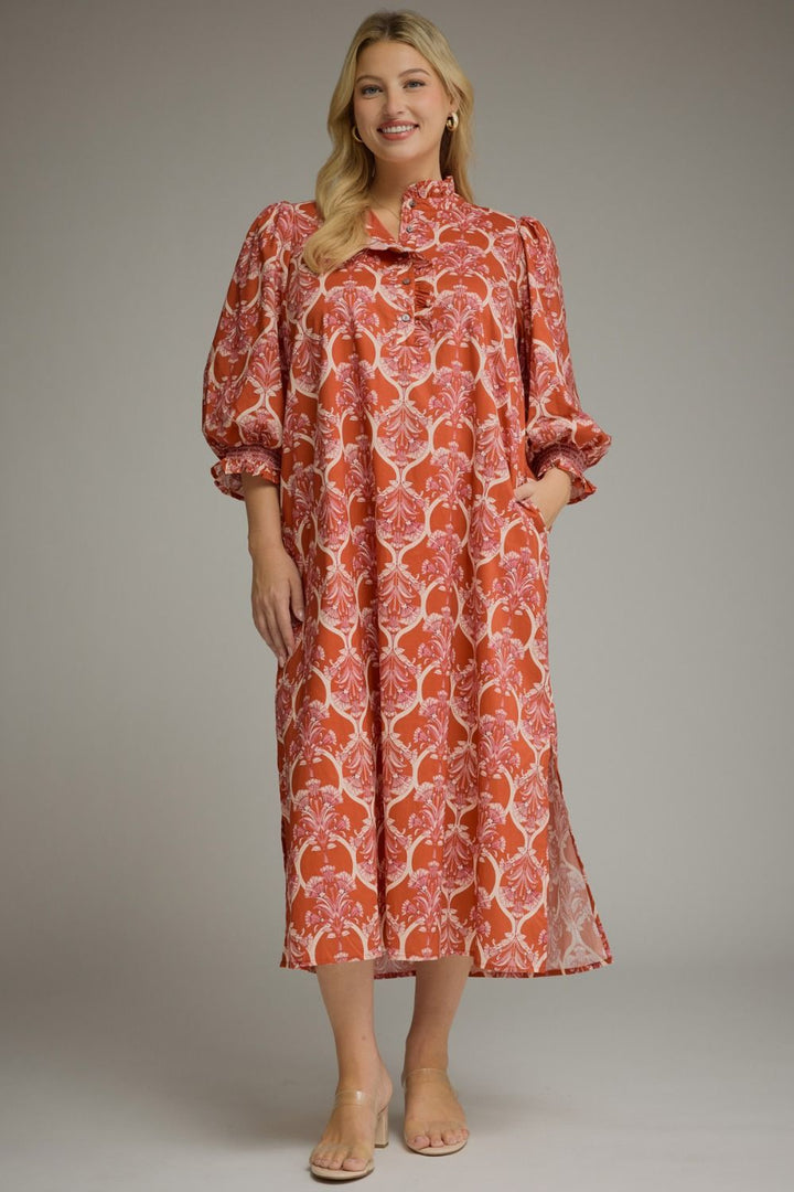 Nora Ruffle Midi Dress in rust-colored intricate print with high ruffle collar, balloon sleeves, and side slits. Available in various sizes.