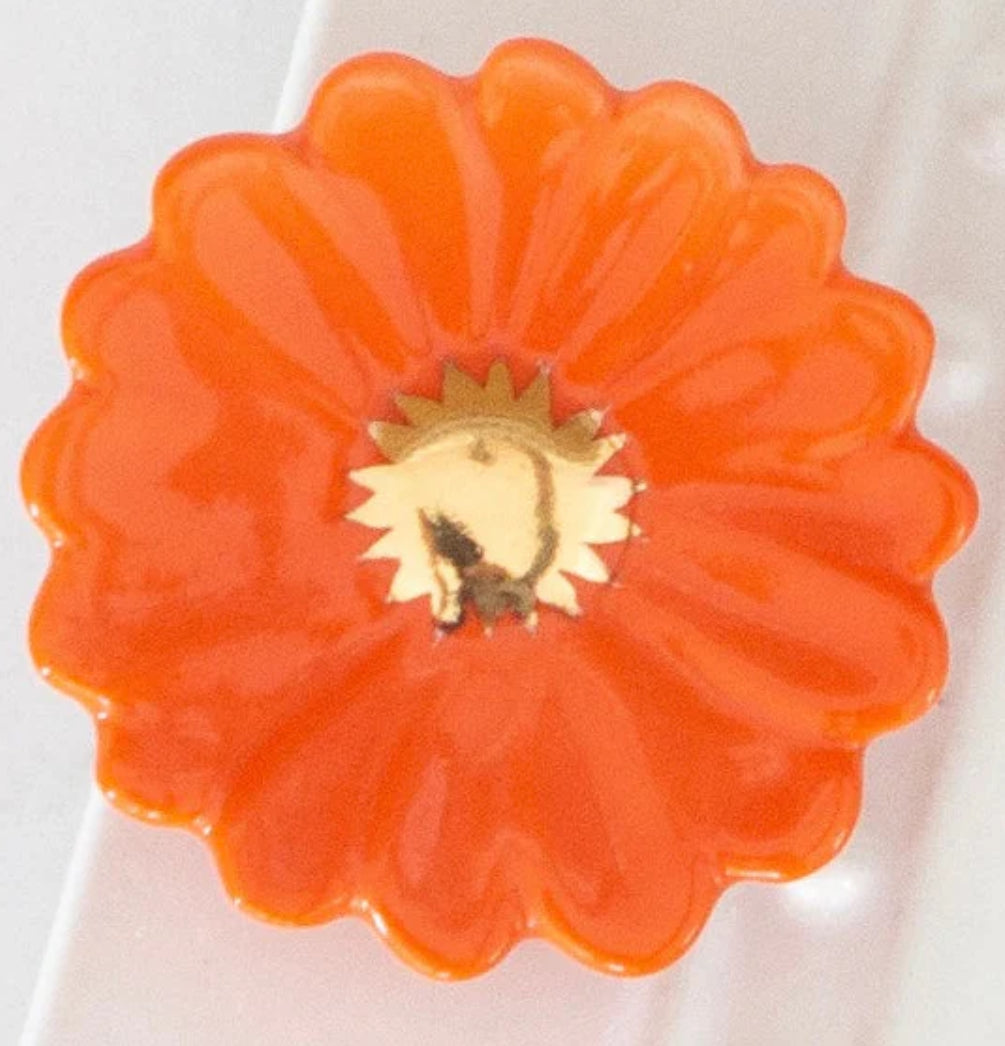 Orange, flower-shaped Nora Fleming Mini with scalloped edges and gold center. Available sizes: mini only.