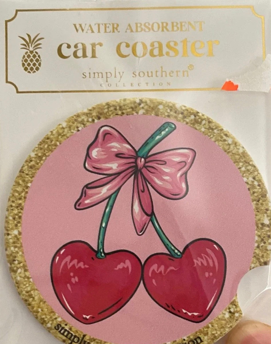 Round cork car coaster with two red cherries tied by a pink bow. Size: fits standard cup holders.