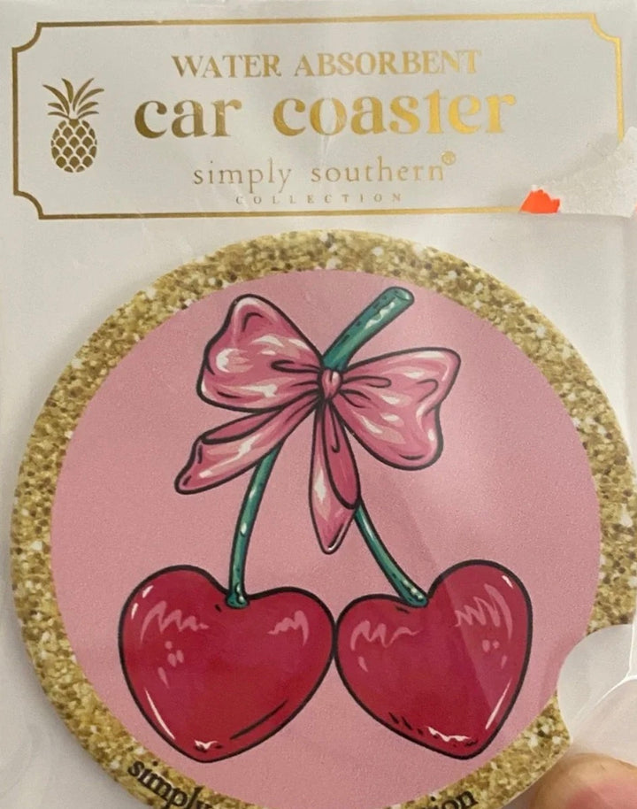 Round cork car coaster with two red cherries tied by a pink bow. Size: fits standard cup holders.
