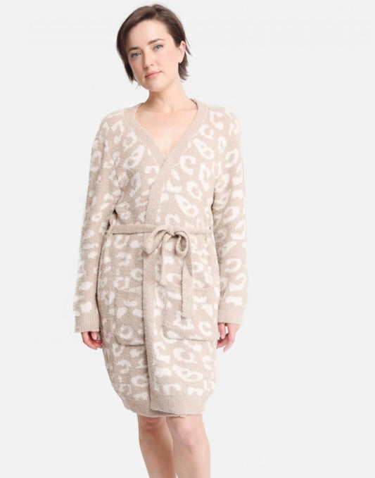 A woman stands confidently wearing a beige leopard print Comfy Luxe Robe with a deep v-neck, tied at the waist with a matching belt. Her short dark hair complements her poised, direct