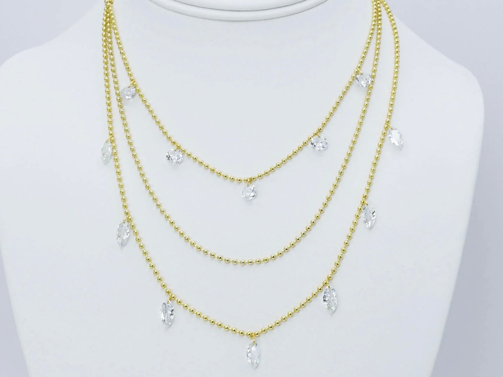 Three gold beaded chains with clear teardrop crystal pendants. Available in 16", 18", and 20" lengths.