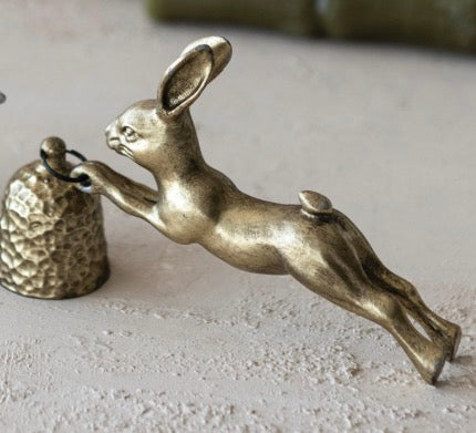 Pewter Rabbit Shaped Candle Snuffer in antique gold finish, leaping rabbit holds a textured snuffer by a ring. Sizes: S, M.
