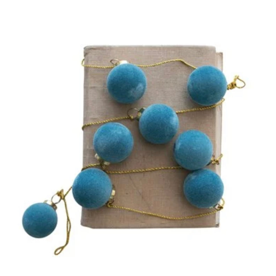 Flocked glass ball ornament garland on gold cord.