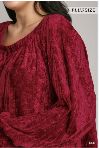 This Velvet High Low Long Sleeve Top in red features a draped design and intricate shoulder detail. Available sizes for this top range from small to extra large.