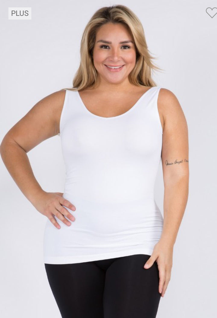 A confident woman smiles, her blonde hair complemented by a Reversible V or U Neckline Seamless Tank and black leggings, showcasing a tattoo on her left arm. The image features a sizing label in the corner.