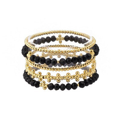 Five layered bracelets from the Gema Black Stretch Bracelet Stack with alternating small gold and larger black beads, plus a bold black bracelet with gold accents. Available in standard stretch sizing.