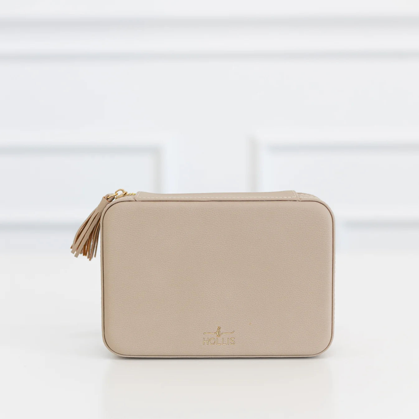 Beige rectangular Hollis zippered pouch with tassel, gold logo, and “HOLIS” on front. Jewelry organizer; available in multiple sizes.