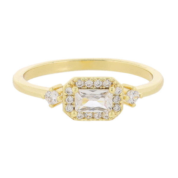 This is an 18K Gold Plated ring adorned with a central square-cut diamond, surrounded by mini crystals. The band is also embellished with additional diamonds. Available in various sizes.
