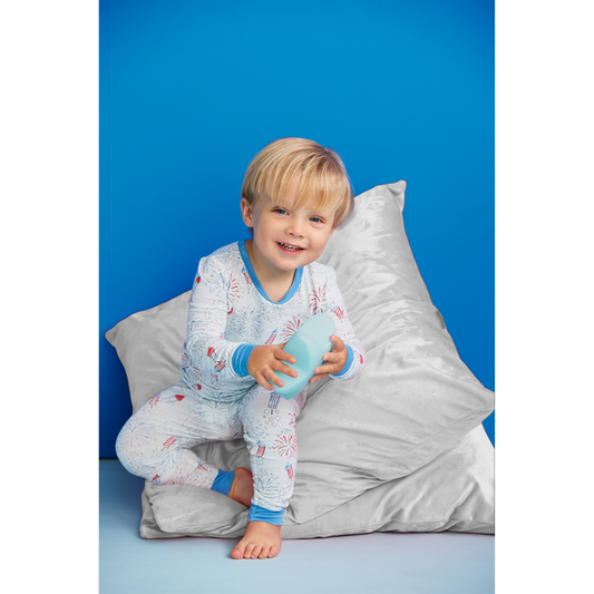 Boy modeling the pajamas sitting on some pillows playing with a star