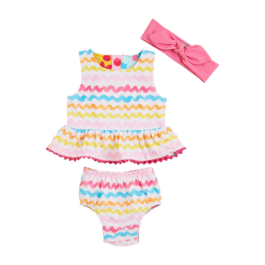 A colorful toddler girl's Rainbow Reversible Swimsuit displayed on a white background, featuring a sleeveless top with zigzag patterned ruffles in pastel colors and matching bloomers, accompanied by a pink bow