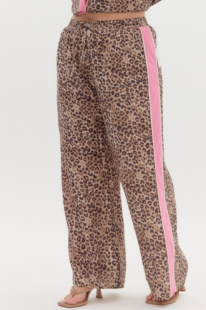 Leopard print pants with pink stripe detail. Available in sizes XS–XL.