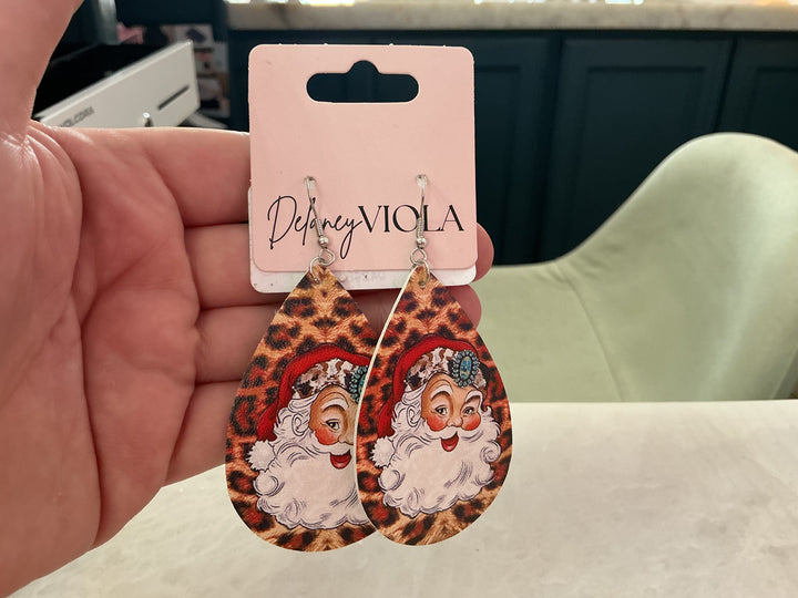 Teardrop-shaped Cheetah Santa Claus earring with cheetah print and Santa portrait featuring a turquoise embellishment. Available in multiple sizes.