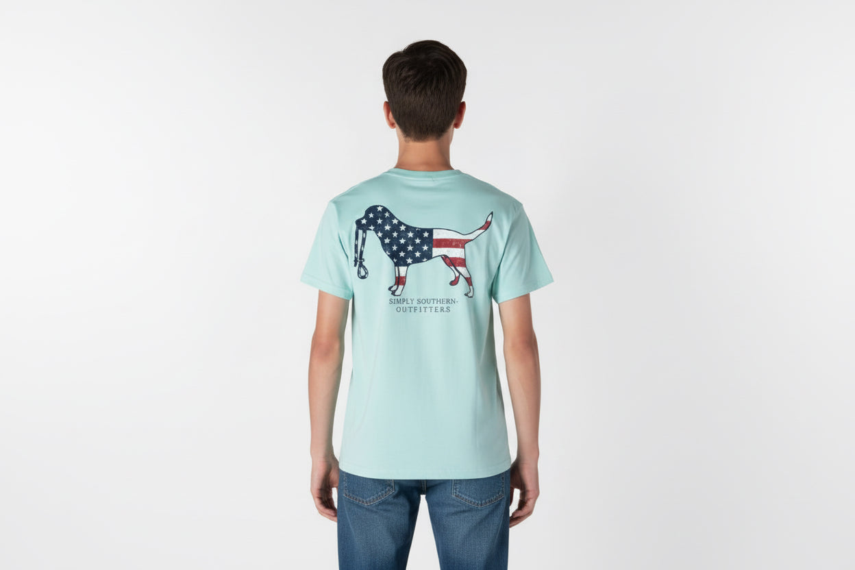 Light blue Men’s Dog USA T-Shirt with flag-filled dog graphic and “SIMPLY SOUTHERN OUTFITTERS” on back. Sizes: S-XXL.
