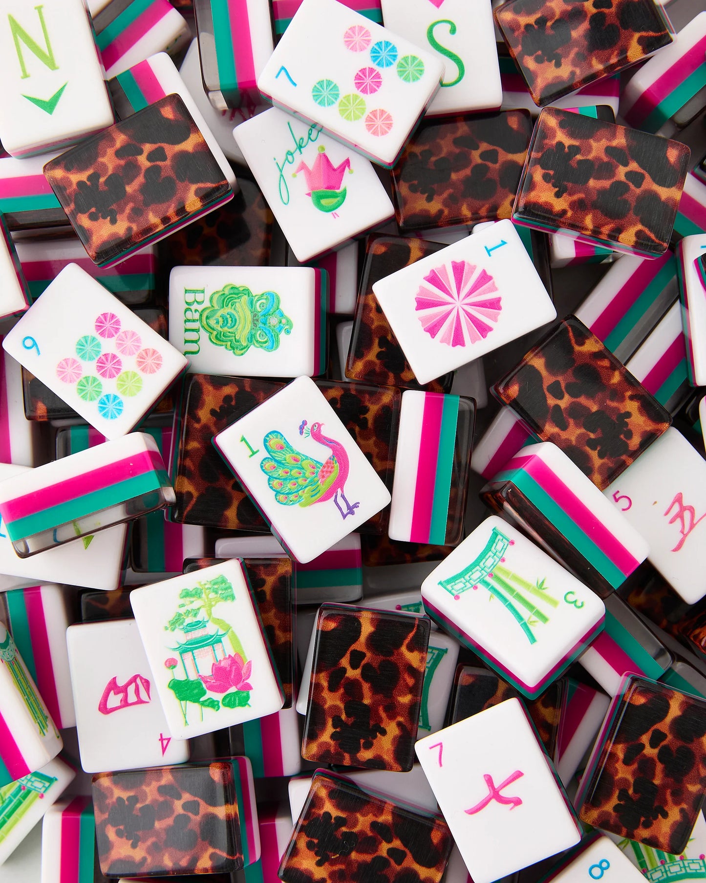 Glow Wild Mahjong Tiles feature leopard-print backs and colorful pink, green, and blue symbols, animals, numbers, and striped patterns in pink, teal, and white. Available in standard tile size.