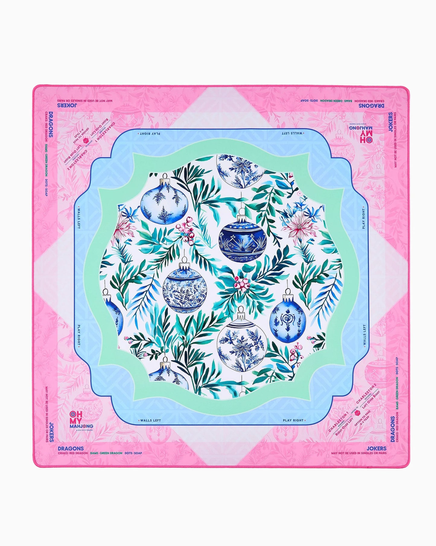 Merriment Mat in Tube: festive table mat with pink border, blue and green inner frames, central floral pattern with blue and white ornaments, and designated playable card areas. Available sizes: standard and large.
