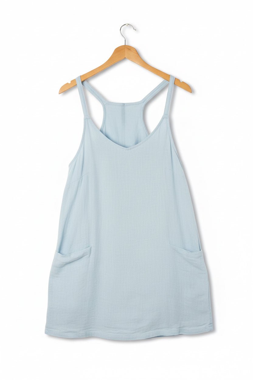 The Tara Dress in Blue: light blue, sleeveless, racerback, two front pockets. Available in sizes XS-XL.