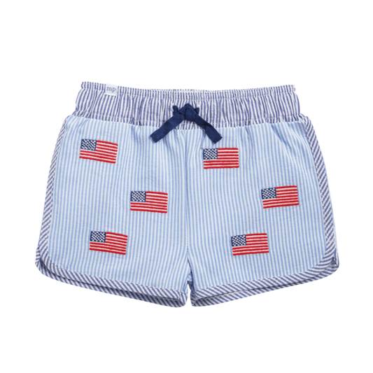 Light blue and white seersucker swim trunks with embroidered flag patches, elastic waistband, navy drawstring. Sizes S-XL.