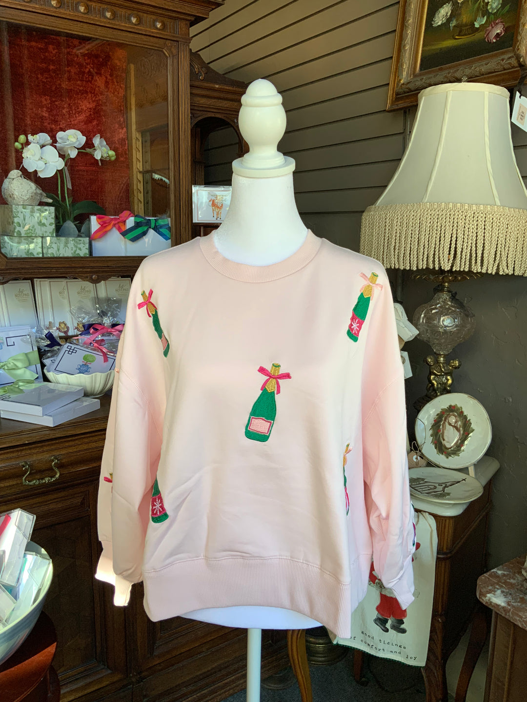 Millie Champagne Sweatshirt, pale pink crewneck with embroidered champagne bottles. Available in multiple sizes.