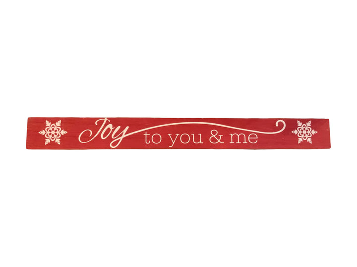 Red rectangular wood Christmas sign with white “Joy to you &amp; me” text and snowflake accents.