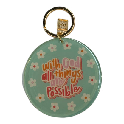 Mary Square Acrylic Keychain: gold ring, teal base, white flowers, “With God all things are possible.” Available in one size.