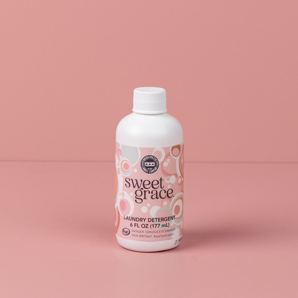 6oz Sweet Grace-Laundry Detergent in a white bottle with pink and white circular label and white cap.
