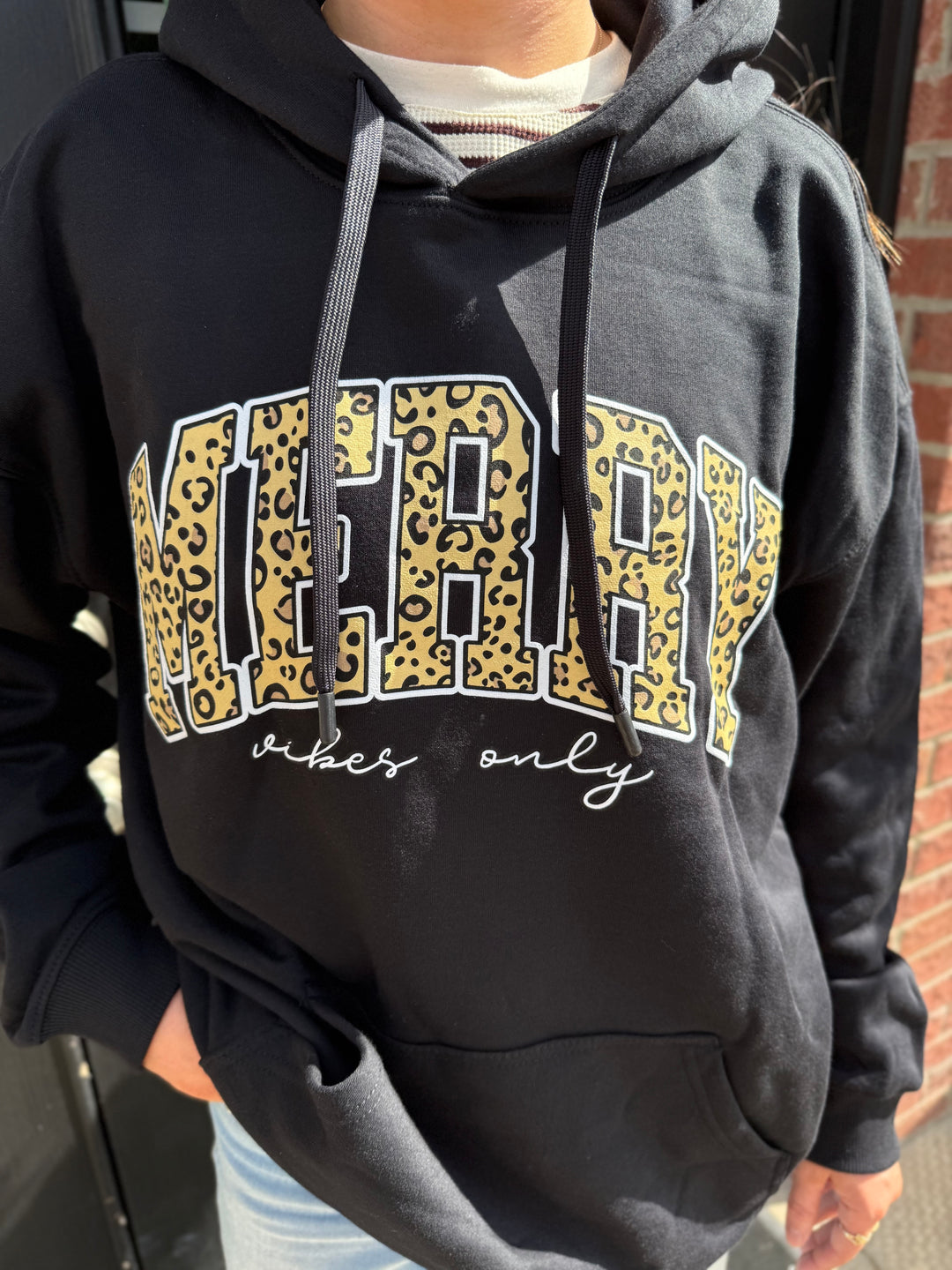 Black Merry Vibes Santa Hoodie with leopard-print “MERRY” graphic and “vibes only” script text. Available in all sizes.