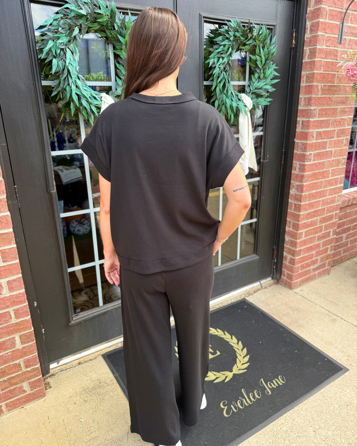 Scout Ribbed Set: black short-sleeved top and wide-leg trousers in ribbed fabric. Available in all sizes.