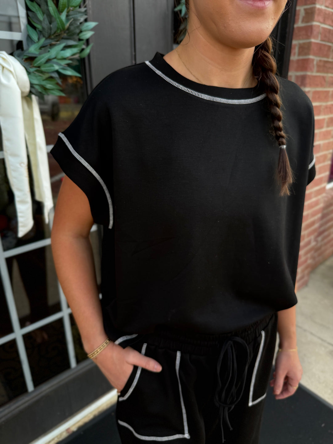 Black scuba lounge set with short-sleeved top, drawstring shorts, and white contrast stitching. Available in multiple sizes.