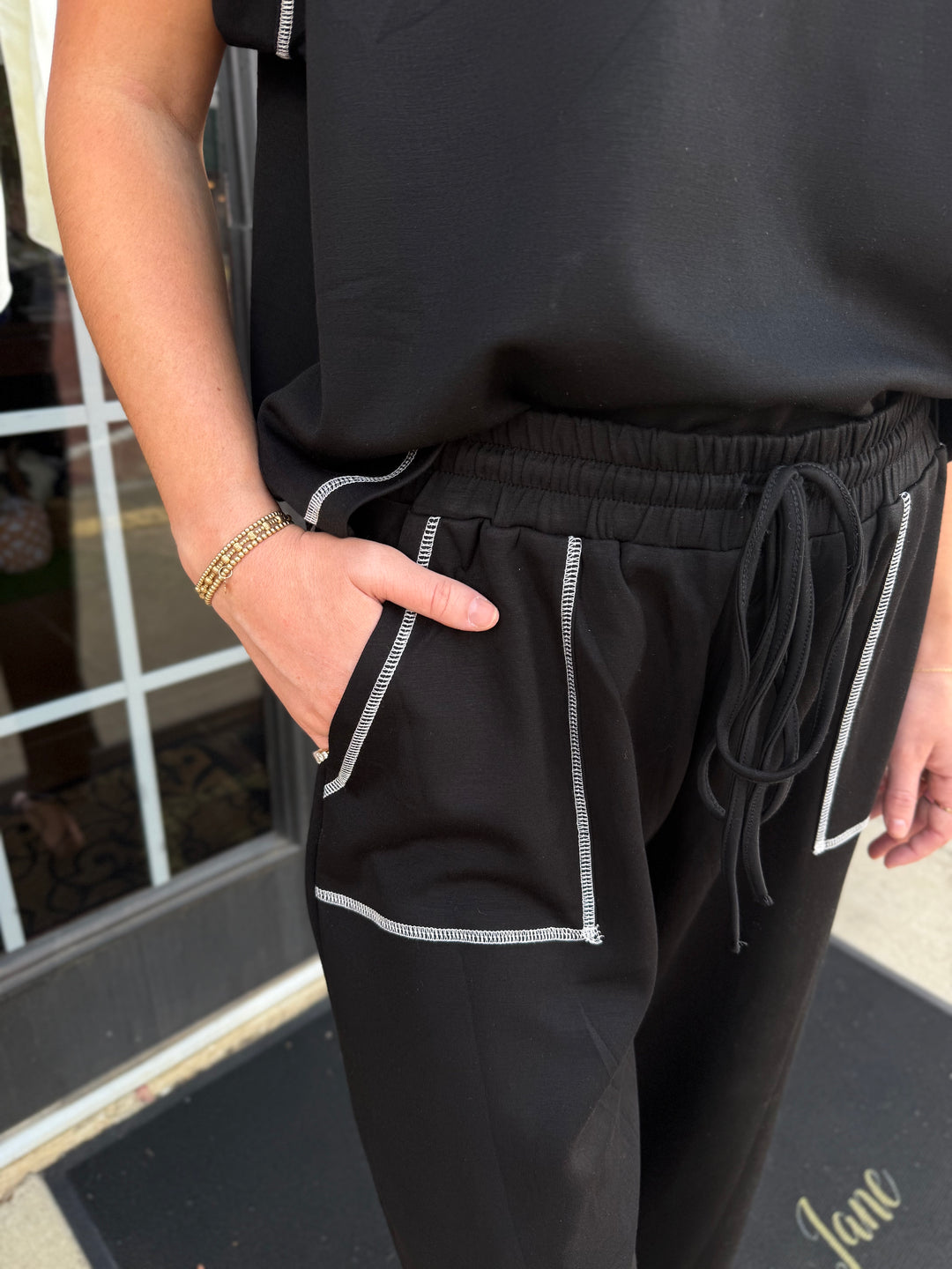 Contrast Stitch Scuba Lounge Set: black short-sleeved top and drawstring wide-leg pants with white contrast stitching and front patch pockets.