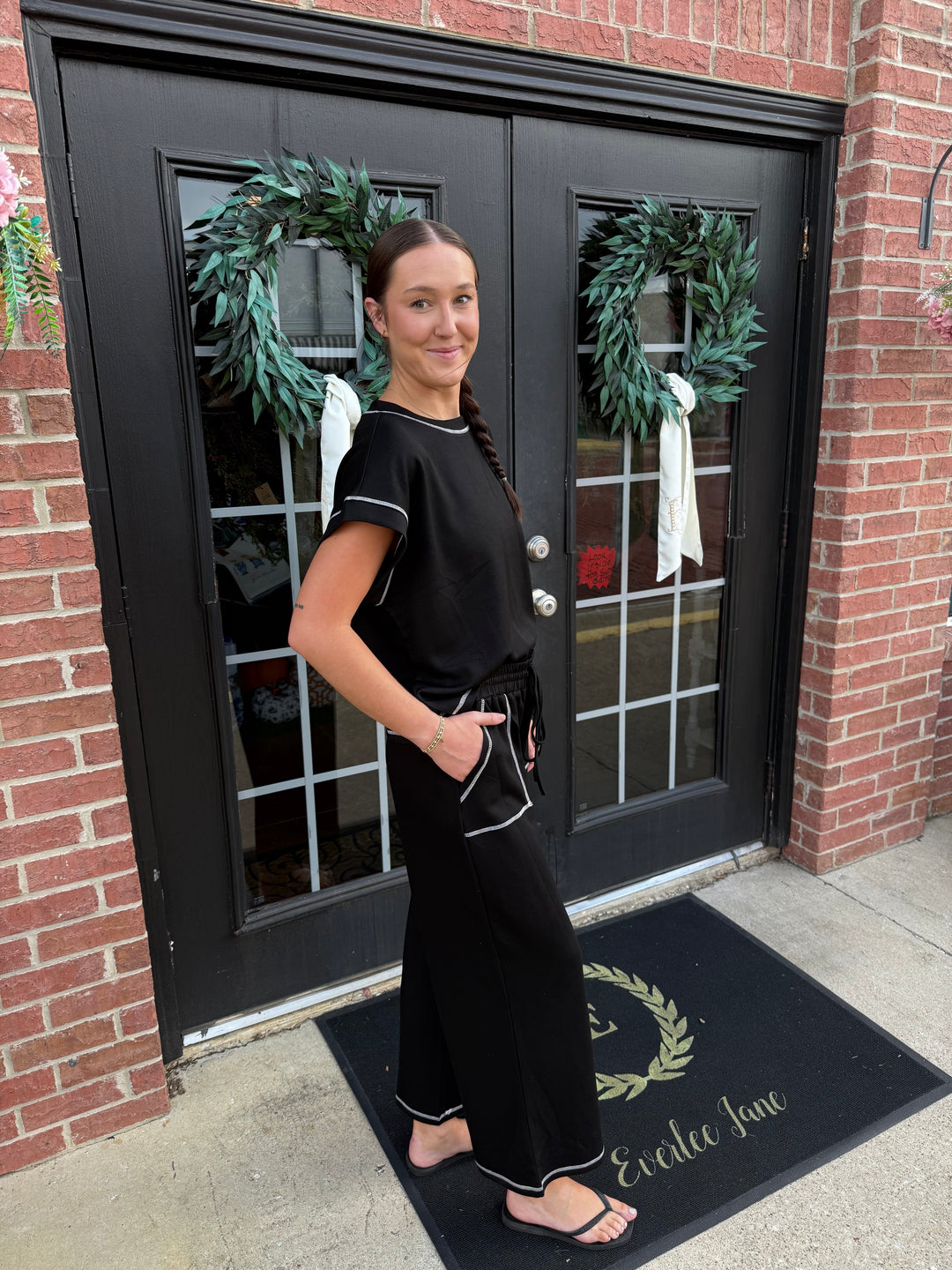 Contrast Stitch Scuba Lounge Set with black short-sleeved top and wide-leg pants featuring white contrast stitching and drawstring waist.