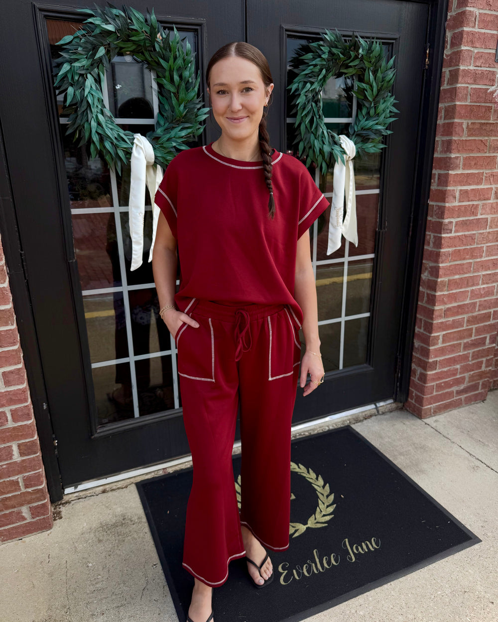 Maroon scuba lounge set with white contrast stitching, short-sleeved top, and wide-leg drawstring pants. Available in various sizes.