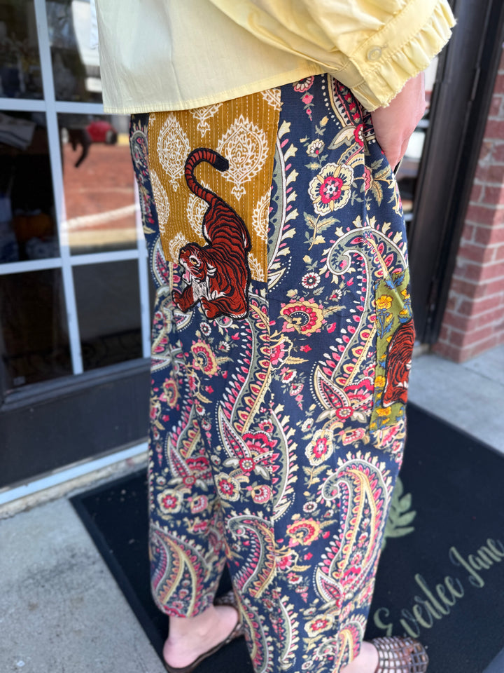 Loose-fitting Tiger Barrel Pant in dark blue paisley with mustard yellow patches and tiger illustrations. Sizes available: [Insert sizes].