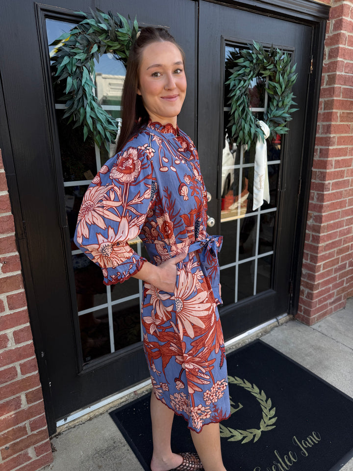 Blue and orange floral midi dress with high ruffled neckline, tie waist, and scallop trim. Available in all sizes.