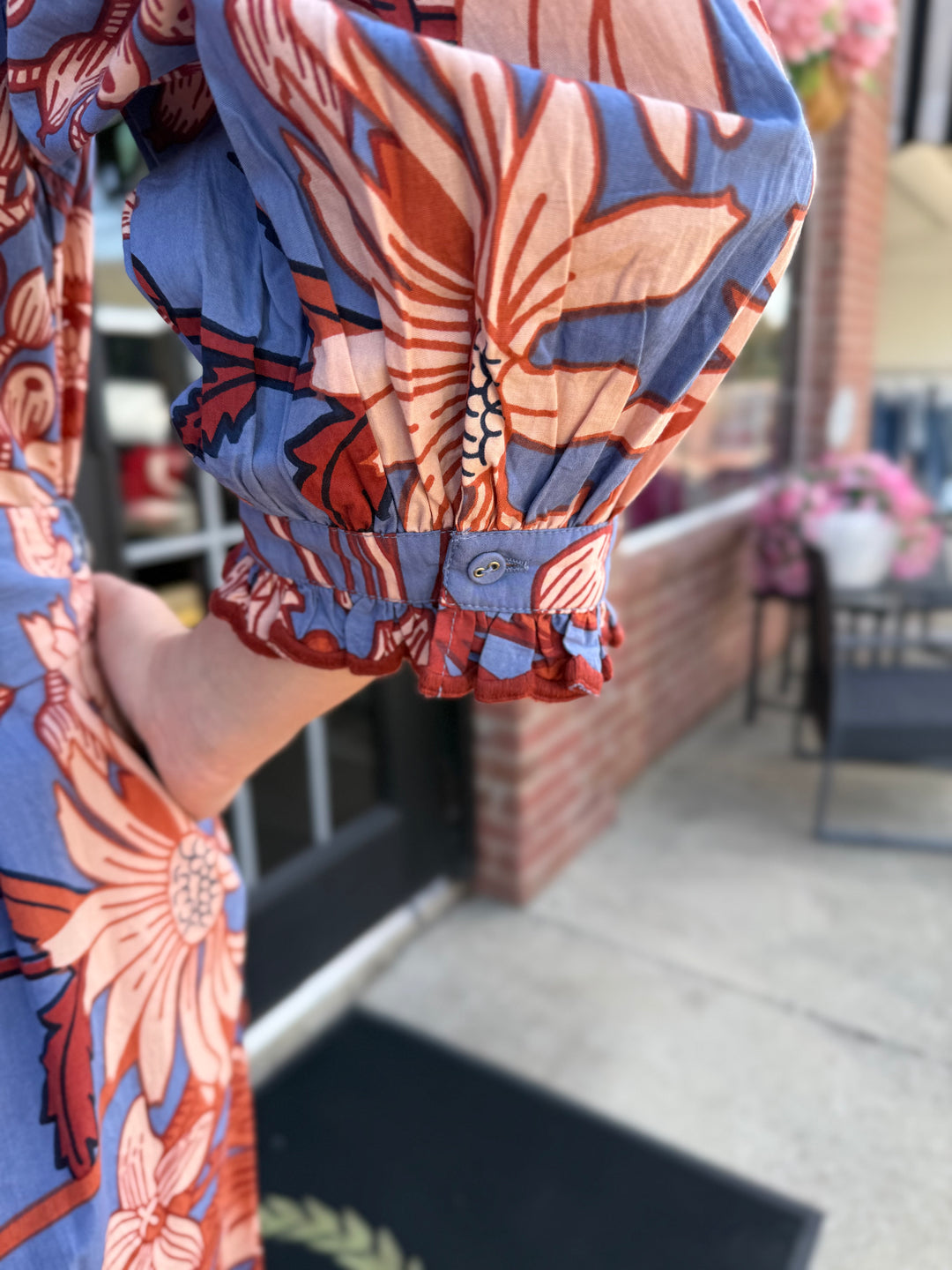 Blue and orange floral midi dress with puff sleeves and buttoned, embroidered scallop trim cuffs. Available in sizes XS-XL.
